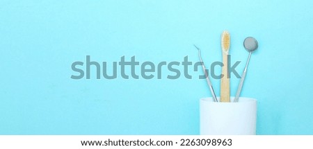 Different tools for dental care, toothbrush in plastic glass. Tooth symbol sign. Dentist's medical equipment tools on blue background.