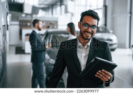 Using graphic tablet. Three people are working together in the car showroom. Royalty-Free Stock Photo #2263099977