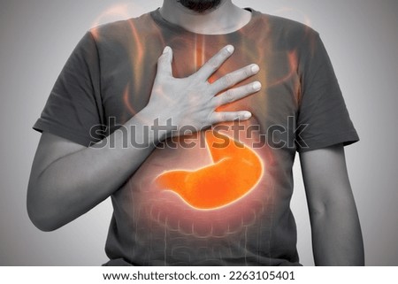 A man burning sensation in chest from acid reflux on gray background. Royalty-Free Stock Photo #2263105401
