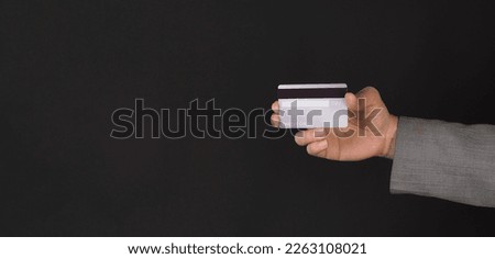 Hand is show back of silver credit card isolated on white background.