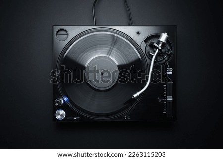 Flat lay photo of DJ turntable playing vinyl record on black background. Professional analog record player shot directly from above Royalty-Free Stock Photo #2263115203