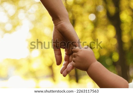 Daughter holding mother's hand outdoors, closeup. Happy family Royalty-Free Stock Photo #2263117563