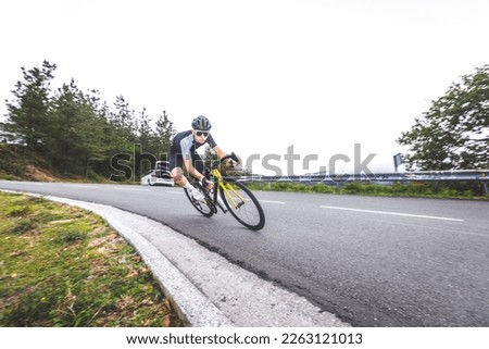 Young caucasian man going downhill on a corner with a road bike on an asphalt road of a mountain.