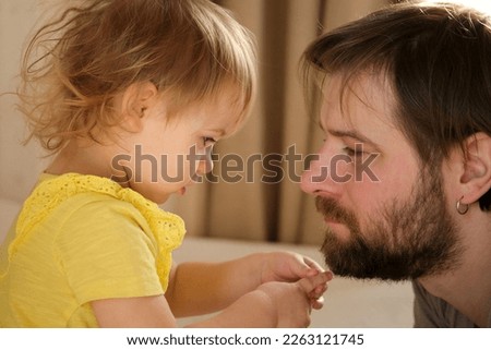 Happy Father with Daughter, Tiny Girl. One Year Baby Smiling, Laughing, Looking up at Daddy. Man Showing Affection to Child. Candid Real Emotion. Beard Dad and Little Kid. Authentic Family Lifestyle.