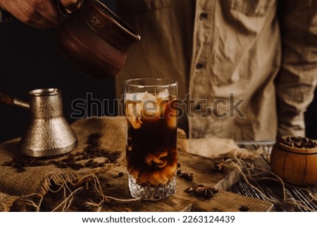 male barista pouring cream or milk into a glass of iced coffee 1