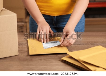 Post office worker sticking barcode on parcel at counter indoors, closeup Royalty-Free Stock Photo #2263125391