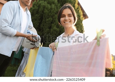 Family hanging clothes with clothespins on washing line for drying in backyard