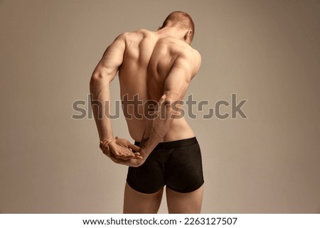 Veins on hands, strength. Male model posing in underwear over grey studio background. Relief, muscular back. Concept of men's health and beauty, body and skin care, fitness. Body art Royalty-Free Stock Photo #2263127507