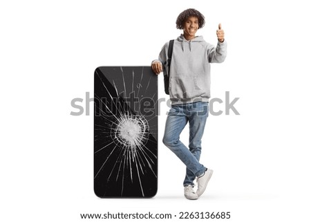 Young african american male student with a big mobile phone with cracked screen gesturing thumbs up isolated on white background