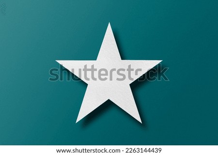 paper cut star shape with light and shadow placed on a green paper background