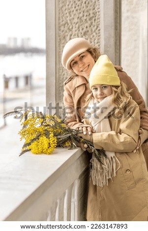 Portrait of mother and little daughter with mimosa bouquet in spring park. Spring, International Women's Day March 8