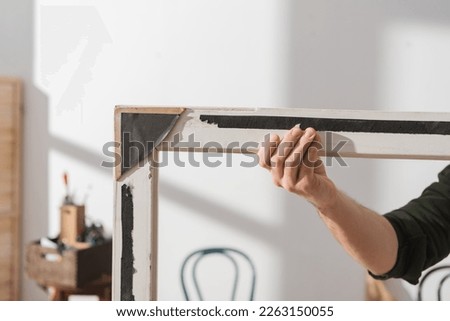 Cropped view of restorer touching wooden frame in workshop