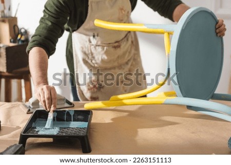 Cropped view of restorer repainting wooden chair on table Royalty-Free Stock Photo #2263151113