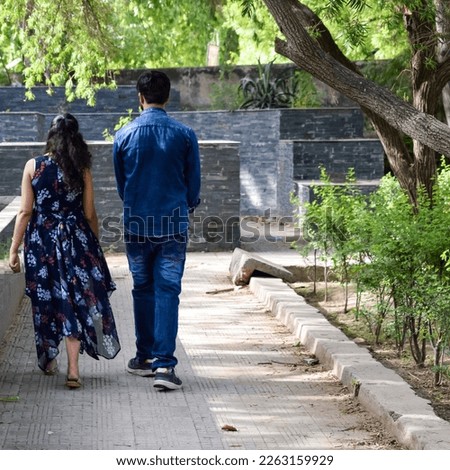 Indian couple posing for maternity baby shoot. The couple is posing in a lawn with green grass and the woman is falunting her baby bump in Lodhi Garden in New Delhi, India