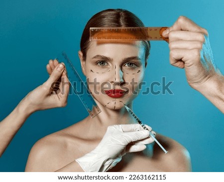 Making beauty, modifying face to make non-surgical or surgical correction, plastic surgery. correction of asymmetry. Young woman, female patient isolated on blue studio background. Concept of lifting Royalty-Free Stock Photo #2263162115