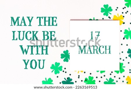 May The Luck Be With You. Composition for St. Patrick's Day. Congratulatory white card calendar with clover on a white background. Top view, lie flat, copy space