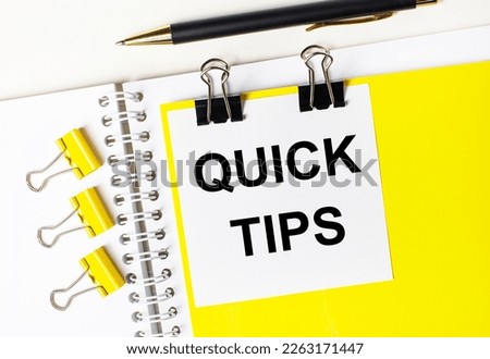 On a light desktop, a pen, yellow paper clips and a white card with the text QUICK TIPS on a yellow background