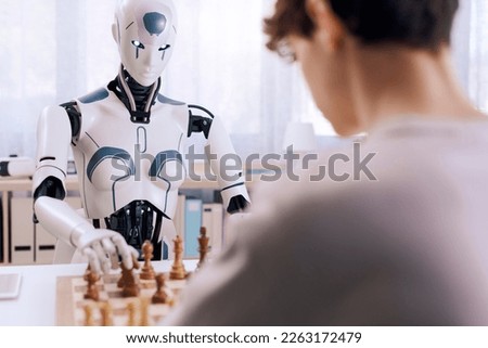 A futuristic chess match between boy and robot takes place. Royalty-Free Stock Photo #2263172479