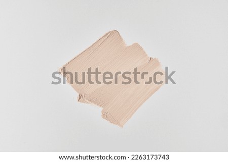 One cosmetic touch of foundation. Perfection of the skin. The concept of beauty, cosmetology and makeup. Design template, poster for advertising on light grey background. Copy space.High quality photo