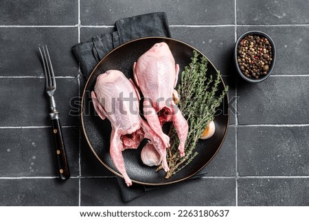 Fresh organic quails, raw poultry with herbs. Black background. Top view.