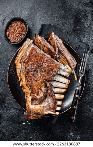 Roasted Rack of lamb ribs, mutton spareribs, sliced meat on plate. Black background. Top view. Royalty-Free Stock Photo #2263180887
