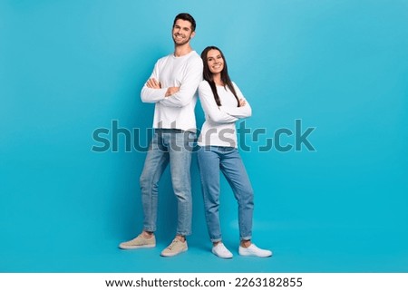 Full length portrait of two positive cheerful people crossed arms isolated on blue color background