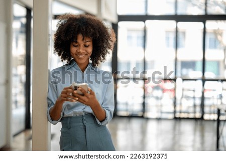 Portrait of smiling black woman with smart phone enjoys online chatting types text message surfs social networks