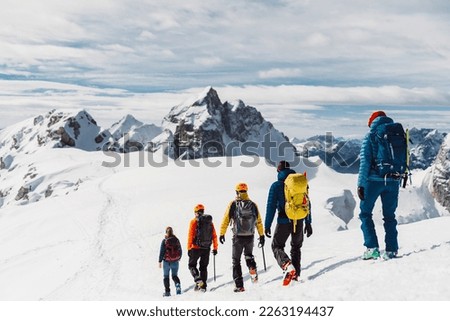 View from the back, five mountaineers descending down the snowy mountain, walking in a row  Royalty-Free Stock Photo #2263194437