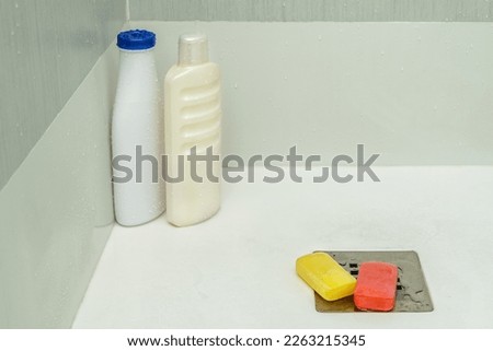 Shower cabin with stainless steel drain with glycerin soap bars and shampoo bottles with water drops