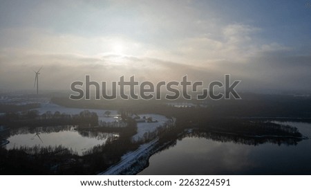 Aerial landscape of the frozen lake and forest in the snow in Belgium at sunset shot by a drone. High quality photo