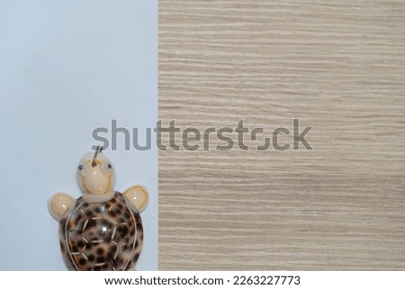 Flat background white paper and wooden motive with turtle keychain toy