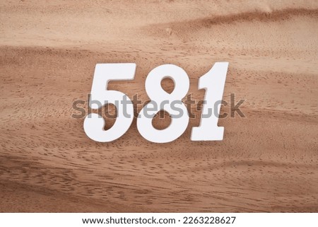 White number 581 on a brown and light brown wooden background.