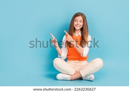 Full length photo of positive cute lady sitting floor presenting empty space novelty feedback isolated on blue color background