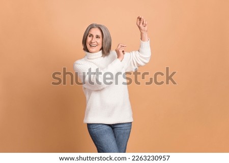 Photo of carefree dancing motion pensioner woman dance overjoyed hands moves up chill party wear white sweater isolated on beige color background