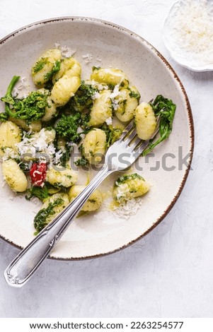 Gnocchi with  turnip leaves and tops or cima di rapa with chili pepper, olive oil and  Parmesan cheese.  Mix  recipes of south, Puglia, and nord of Italy.  White table, top view Royalty-Free Stock Photo #2263254577