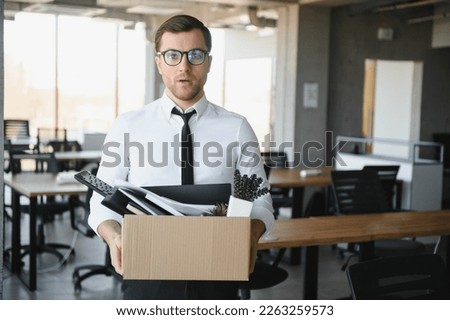 Sad Fired. Let Go Office Worker Packs His Belongings into Cardboard Box and Leaves Office. Workforce Reduction, Downsizing, Reorganization, Restructuring, Outsourcing. Mass Unemployment Market Crisis. Royalty-Free Stock Photo #2263259573