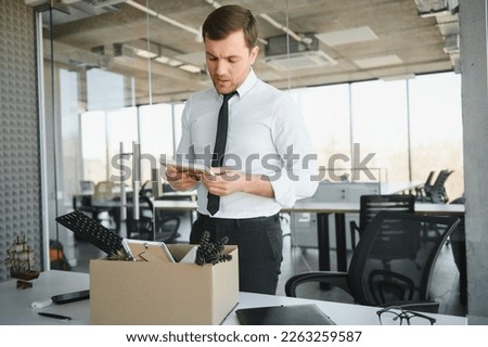 Sad Fired. Let Go Office Worker Packs His Belongings into Cardboard Box and Leaves Office. Workforce Reduction, Downsizing, Reorganization, Restructuring, Outsourcing. Mass Unemployment Market Crisis. Royalty-Free Stock Photo #2263259587