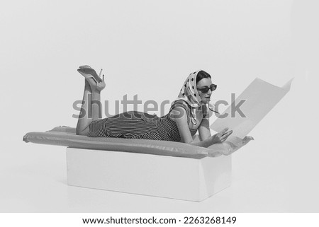 Summer vacation. Monochrome portrait of young beautiful woman lying on inflatable mattress and reading magazine. Retro vintage style, 70s, 80s fashion. Copy space for ad Royalty-Free Stock Photo #2263268149