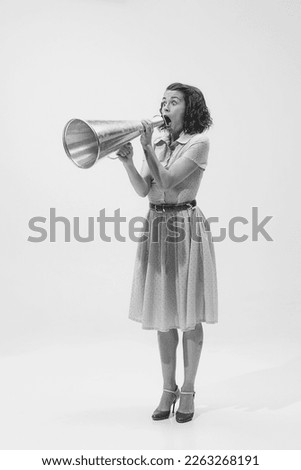 Black and white portrait of young beautiful woman shouting expressively in megaphone. Big sales, news. Concept of beauty, retro style, fashion, elegance, 60s, 70s, shout. Copy space for ad Royalty-Free Stock Photo #2263268191