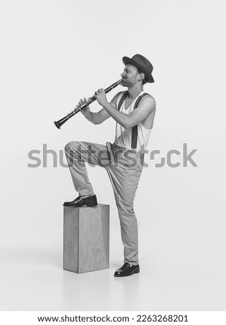 Portrait of young retro man playing clarinet. Improvisation. Expressive performance. Concept of live music, performance, retro style, creativity, artistic lifestyle. Black and white photography Royalty-Free Stock Photo #2263268201