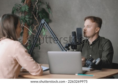 man and woman in studio record podcast, create audio content, advertising message. male radio host wearing headphones with microphone interviews female guest and tells news. digital