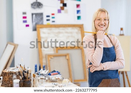 Young woman is in her painting studio. She is posing for the portrait photo of her working there