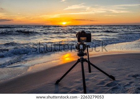Professional camera and tripod filming colorful sunset and nobody in Gulf of Mexico coast with water waves in Seaside Santa Rosa Beach, Florida panhandle and reflection Royalty-Free Stock Photo #2263279053