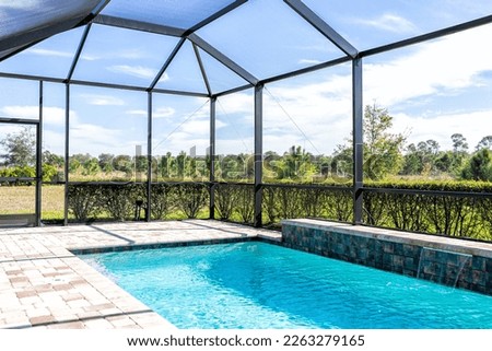 Modern contemporary home villa with screened in glass canopy lanai private pool with view of tropical lake in Florida with blue water in clean house Royalty-Free Stock Photo #2263279165