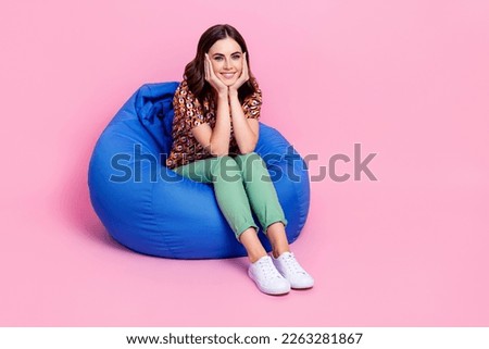 Full body size photo of cute lovely toothy beaming smile girl touch cheeks sitting beanbag comfortable relax dreamy isolated on pink color background