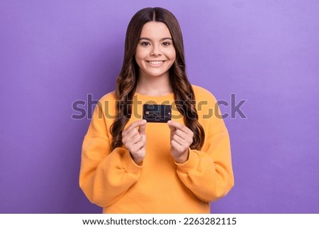 Photo of positive pretty lady wear orange sweatshirt holding credit card isolated violet color background