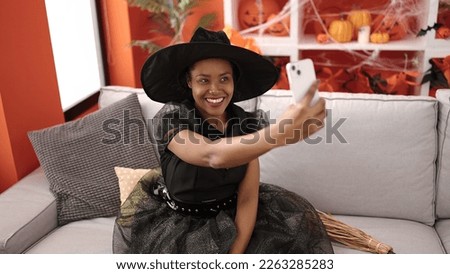African american woman wearing witch costume make selfie by smartphone at home
