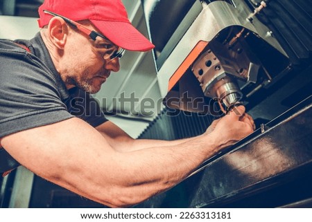 Professional CNC Laser Machine Operator Performing Equipment Cutting Head Check. Metalworking Industry. Royalty-Free Stock Photo #2263313181