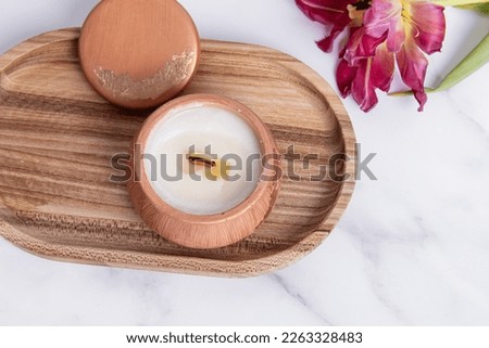 Interior candle in plaster candlestick and tulip on marble background. Candle on wooden tray. Top view