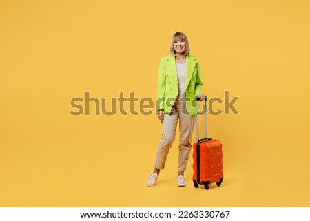 Full body elderly woman 50s years old wearing green jacket white t-shirt hold valise isolated on plain yellow background. Tourist travel abroad in free spare time rest. Air flight trip journey concept Royalty-Free Stock Photo #2263330767